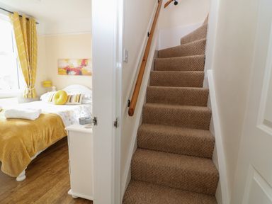 A bedroom with a bed and nightstand next to a carpeted staircase at The Cottage at Broadway in Broadway