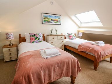 A bedroom with two single beds a dresser two bedside tables and a skylight window at The Cottage at Broadway