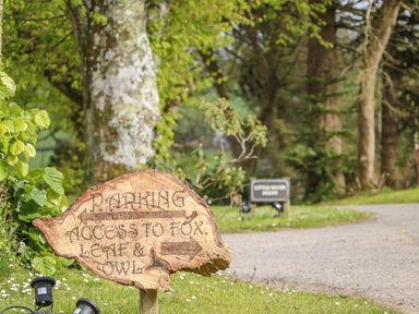 A wooden parking sign directing to fox leaf and owl with trees and a gravel road in the background at Little Silver Owl in High Bickington