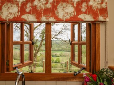 A wooden framed window with two panes open overlooking green fields at Little Silver Owl in High Bickington