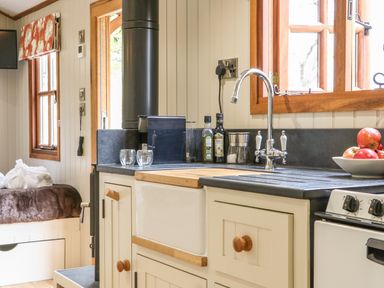 A kitchen corner with a sink a stove a window bottles and a bowl of apples at Little Silver Owl in High Bickington