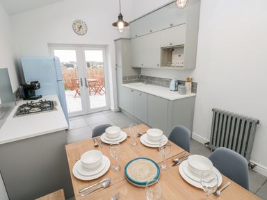 A kitchen with a dining table set for four and a blue refrigerator at Coeden Bach in Burry Port