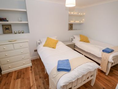 A bedroom with two single beds and yellow cushions at Coeden Bach in Burry Port