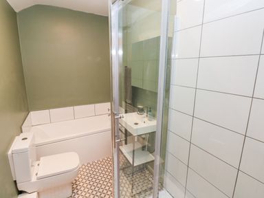 A bathroom with a toilet bathtub sink and glass shower enclosure at Coeden Bach in Burry Port