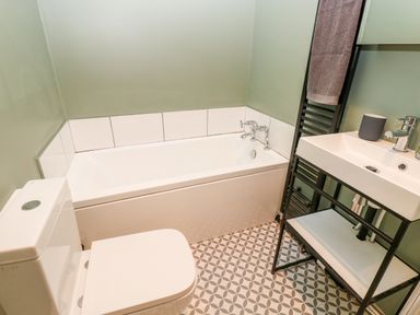 A bathroom with a bathtub toilet sink and towel hanging on rack at Coeden Bach in Burry Port