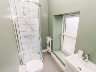A bathroom with a toilet shower cubicle sink and frosted window at Coeden Bach in Burry Port
