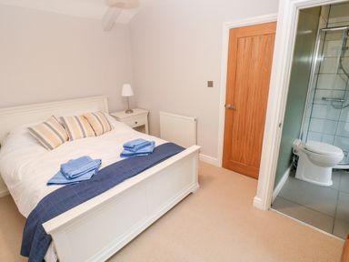 A bedroom with a white bed and blue towels with an ensuite bathroom at Coeden Bach in Burry Port