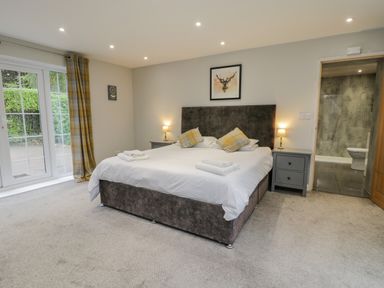 A bedroom with a large bed two bedside tables lamps and an ensuite bathroom at The Manor House in Scarborough