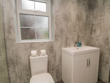 A bathroom with a toilet under a window and a sink with a cabinet at The Manor House in Scarborough