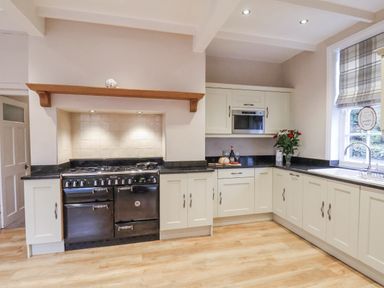 A kitchen with an oven, cabinets, and sink at The Manor House in Scarborough