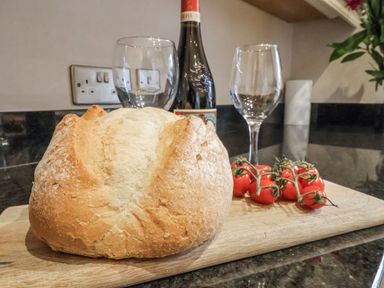 A kitchen with bread, wine glasses, tomatoes, and a wine bottle at The Manor House in Scarborough