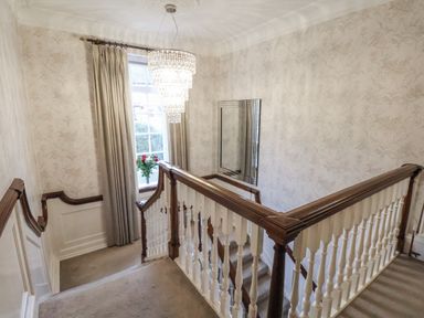 A staircase with a chandelier and mirror in the hallway at The Manor House in Scarborough