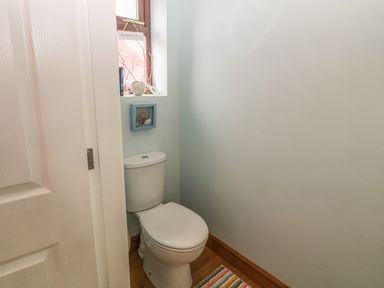 A small bathroom with a toilet and a window at Sea-Prize View in Old Colwyn