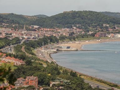 A coastal town with a beach a road and houses surrounded by hills at Sea-Prize View in Old Colwyn