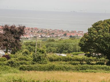 A coastal town with houses near the sea and wind turbines in the water at Sea-Prize View in Old Colwyn