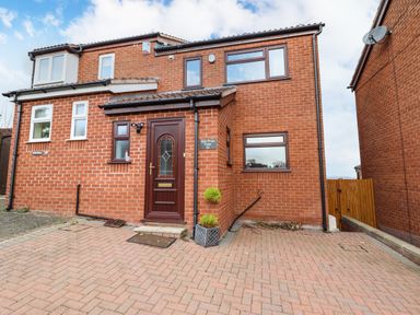 A brick house with a brown front door and driveway at Sea-Prize View in Old Colwyn