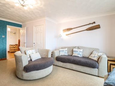 A living room with two sofas cushions and wooden paddles on the wall at Sea-Prize View in Old Colwyn