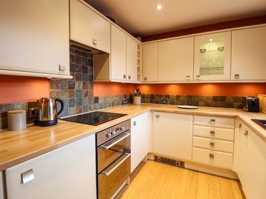 A kitchen with white cabinets wooden countertops an electric stove and oven a kettle and a toaster at Sea-Prize View in Old Colwyn