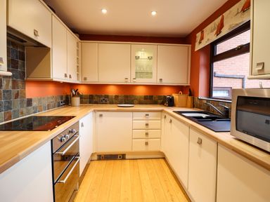 A kitchen with a stovetop oven microwave utensils and a window at Sea-Prize View in Old Colwyn