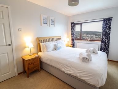 A bedroom with a double bed bedside tables lamps and a window with curtains at Sea-Prize View in Old Colwyn