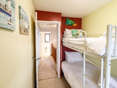 A small bedroom with bunk beds wall art and an open door leading to a hallway at Sea-Prize View in Old Colwyn