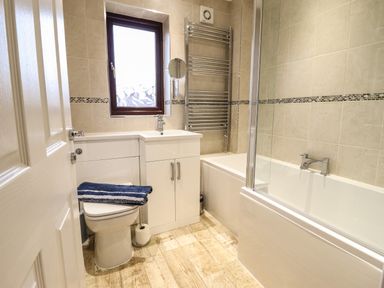 A bathroom with a toilet a sink a bathtub a window and a towel rack at Sea-Prize View in Old Colwyn