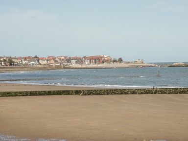 A beach with sand and a breakwater with houses and buildings along the coastline at Sea-Prize View in Old Colwyn