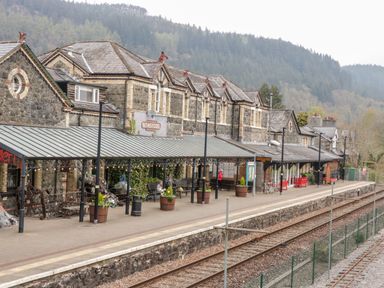 A train station platform with benches, flower pots, and a covered waiting area at Betws-y-Coed