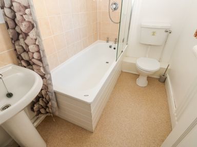A bathroom with a bathtub shower toilet and pedestal sink at Dale View Cottage in Allendale near Hexham