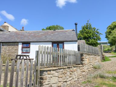 A cottage with a stone wall and wooden fence with a picnic table outside at Dale View Cottage in Allendale near Hexham