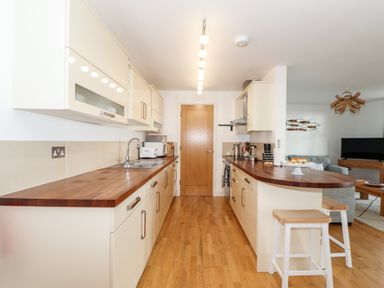 A kitchen with wooden countertops stools and appliances at Ocean Blue in Praa Sands