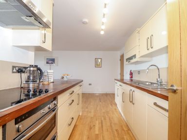 A kitchen with wooden countertops a stove kettle sink and cabinets at Ocean Blue in Praa Sands