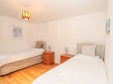 A bedroom with two single beds bedside tables and lamps at Ocean Blue in Praa Sands