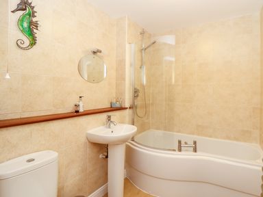 A bathroom with a toilet sink bathtub and seahorse wall decoration at Ocean Blue in Praa Sands