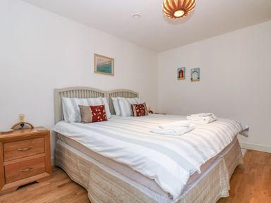 A bedroom with a double bed two bedside tables and framed pictures on the wall at Ocean Blue in Praa Sands
