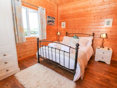 A bedroom with a metal bed frame white bedside tables lamps and a fluffy rug at Borah Lodge in Mousehole