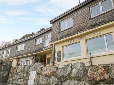 Exterior of cafe at Lamorna Cove with stone wall and building with shingled upper facade