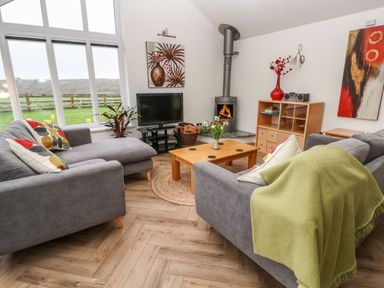 A living room with grey sofas a wooden coffee table and a fireplace at Meadowside in Mousehole