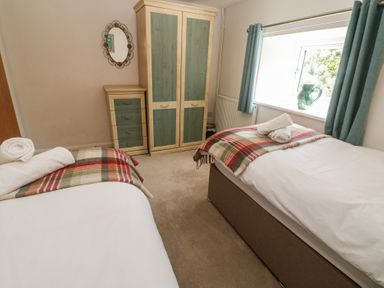 A bedroom with two beds and a wardrobe at Meadowside in Mousehole