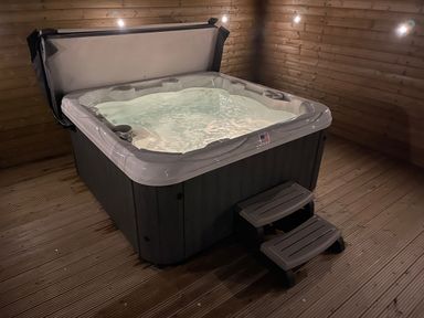 A hot tub with water and steps inside a wooden room at Willow Retallack in Retallack near St Columb Major