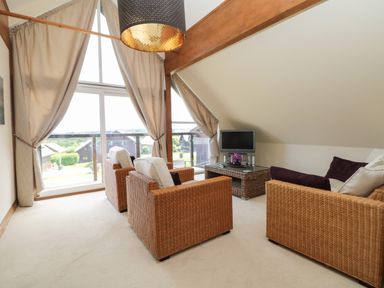 A living room with wicker furniture and a small television at Willow Retallack in Retallack near St Columb Major