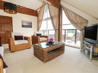 A living room with wicker furniture and a television at Willow Retallack in Retallack near St Columb Major