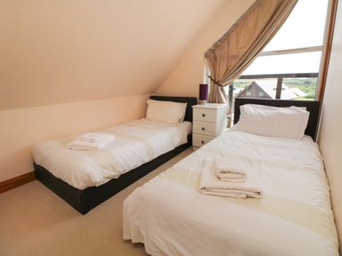A bedroom with two single beds white bedding folded towels and a nightstand with a lamp at Willow Retallack in Retallack near St Columb Major