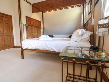 A bedroom with a four-poster bed two wooden doors and a glass side table with a lamp at Willow Retallack in Retallack near St Columb Major