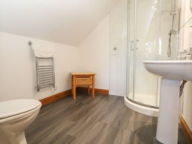 A bathroom with a toilet a towel rack a small wooden table a shower and a sink at Willow Retallack in Retallack near St Columb Major