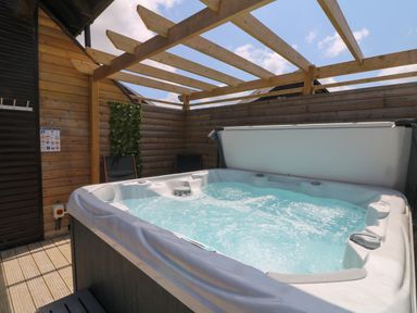 An outdoor hot tub with bubbling water under a wooden pergola at Willow Retallack in Retallack near St Columb Major