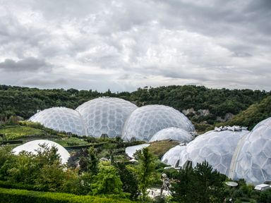 A series of large geodesic dome structures surrounded by green trees and vegetation under a cloudy sky at Willow Retallack in Retallack near St Columb Major