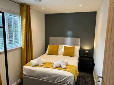 A bedroom with a double bed pillows yellow curtains and a bedside table with a lamp at Willow Retallack in Retallack near St Columb Major