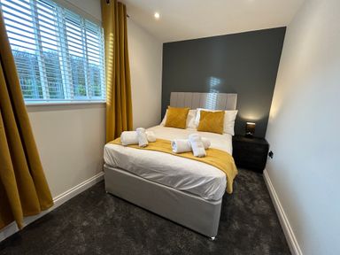 A bedroom with a bed white linens yellow pillows and a yellow runner next to a window with yellow curtains at Willow Retallack in Retallack near St Columb Major