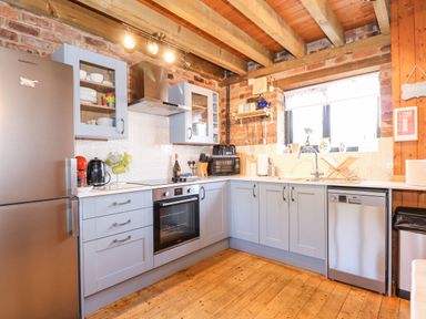 A kitchen with blue cabinets stainless steel appliances and a window at The Dairy Barn in Toftrees near Fakenham